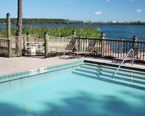 An outdoor swimming pool with chaise lounge chairs alongside the waterfront.