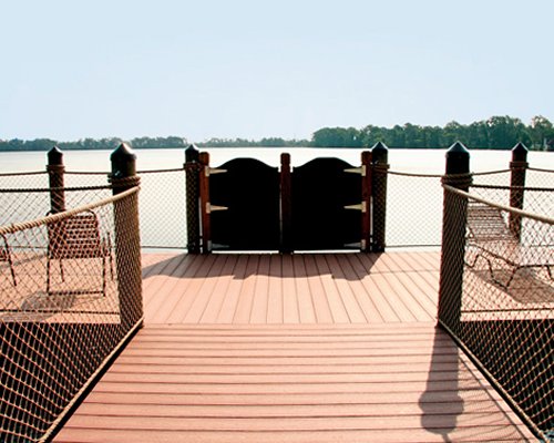Wooden pathway with chaise lounge chairs leading to lake.
