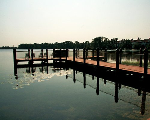A wooden pathway with chaise lounge chairs leading to ocean at dusk.