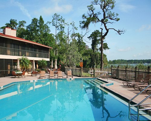 An outdoor swimming pool with chaise lounge chairs sunshades and dining area alongside a unit.