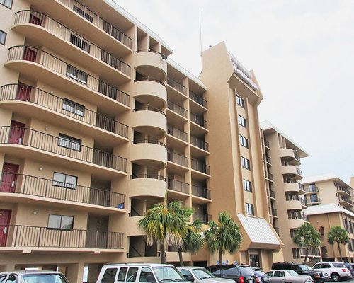 Exterior view of Ocean Towers Beach Club with a parking lot and palm trees.