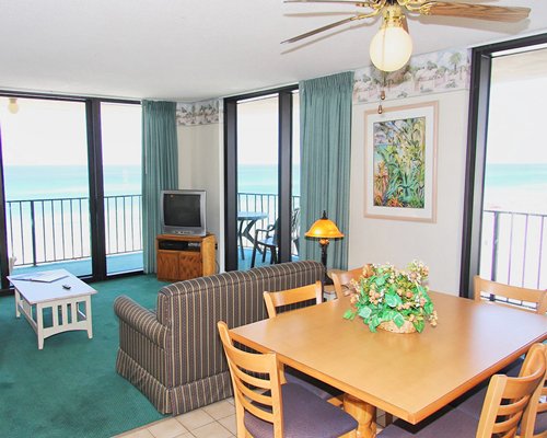 An open plan living room and dining area with a television balcony and ocean view.