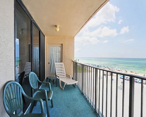 Balcony with patio chairs and beach view.