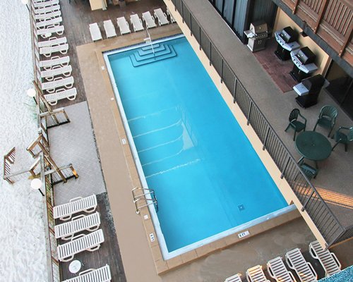An indoor swimming pool with chaise lounge chairs barbecue grill and dining area.