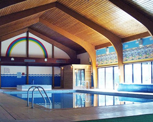 An indoor swimming pool with hot tub and an outside view.