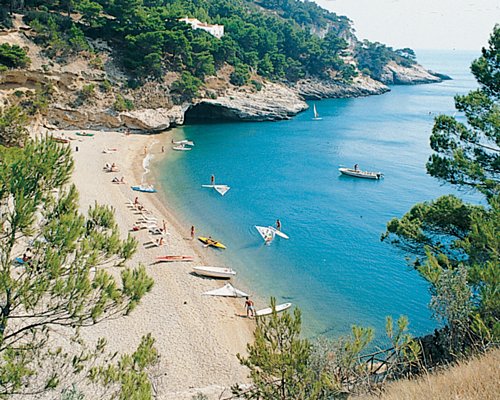An aerial view of the beach with sailboats alongside the ocean.
