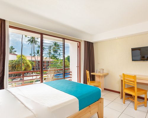 A well furnished bedroom with two beds television and an outside view.