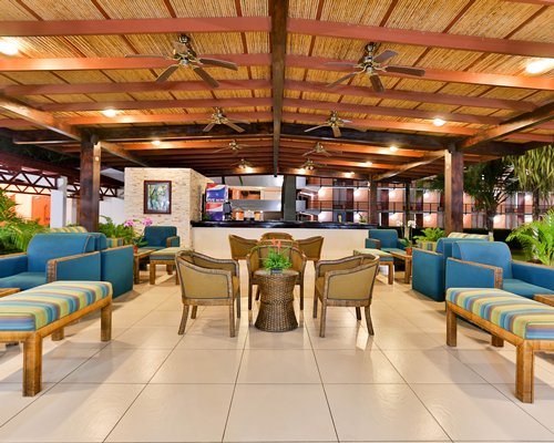 View of chaise lounge chairs sunshades and palm trees alongside Jaco Beach Hotel & Club.