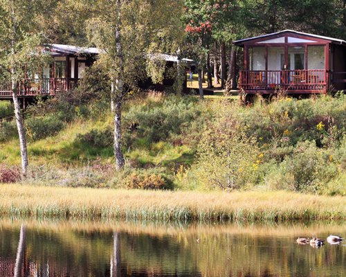 Exterior view of multiple units alongside the river surrounded by wooded area at Macdonald Lochanhully Resort.