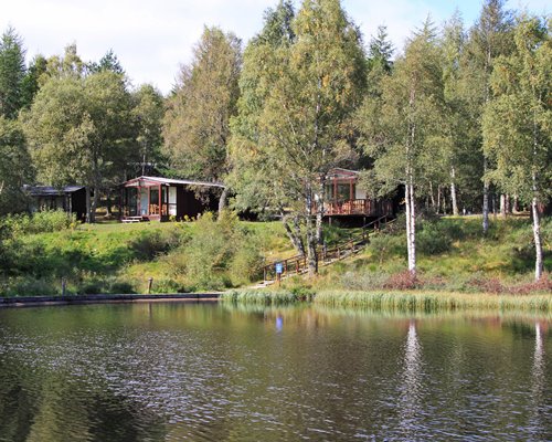 Exterior view of a pathway to units at Macdonald Lochanhully Resort alongside the river surrounded by wooded area.