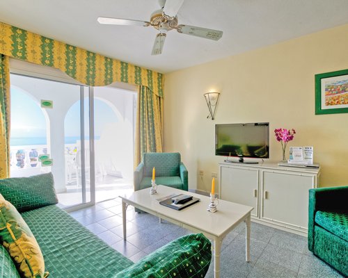 A well furnished living room with a television balcony and ocean view.