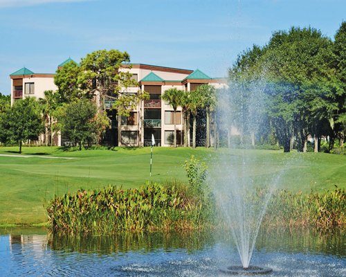A golf course putting green alongside water fountain.