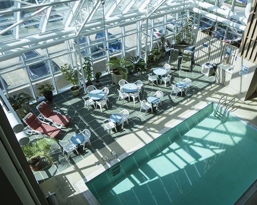 An indoor swimming pool with chaise lounge chairs and patio furniture.