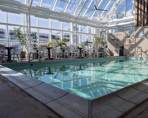 An indoor swimming pool with chaise lounge chairs and patio furniture.
