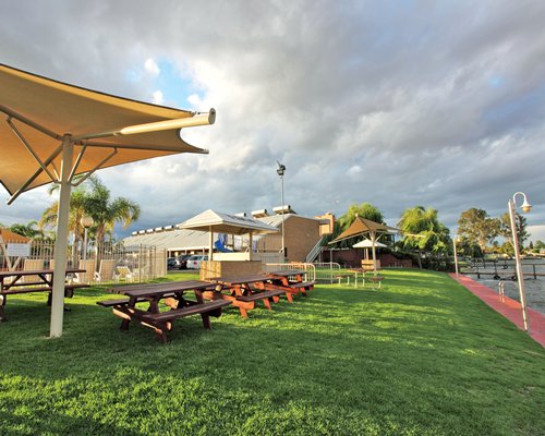 Outdoor picnic area with wooden benches and sunshades.