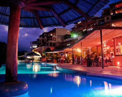 An outdoor swimming pool alongside a restaurant at night.