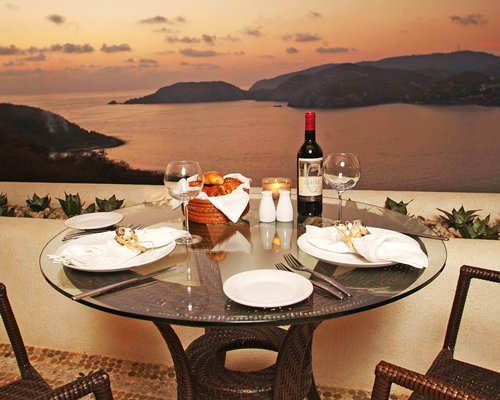 View of food item and beverages on the table with ocean view at dusk.