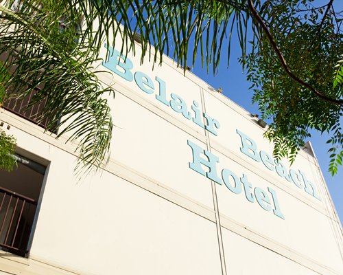 Exterior view of Belair Beach Hotel with palm trees.