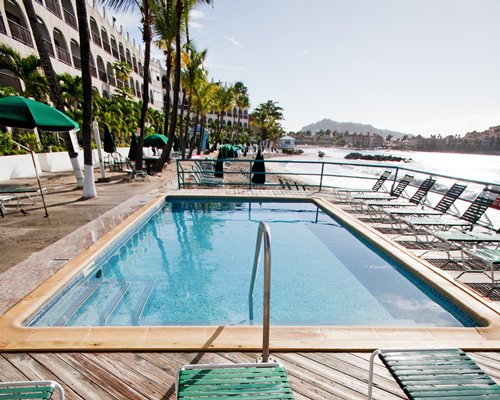 An outdoor swimming pool with chaise lounge chairs sunshades alongside the resort unit.