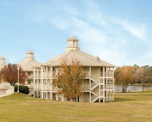 Exterior view of Holiday Inn Club Vacations Piney Shores Resort surrounded by wooded area alongside the lake.