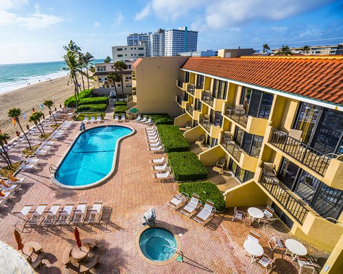 A balcony view of an outdoor swimming pool hot tub and the resort alongside the beach.