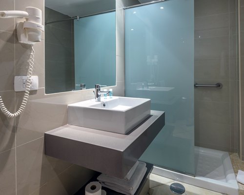 A bathroom with a stand up shower sink and mirror.