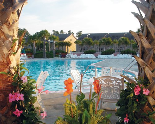Scenic view of an outdoor swimming pool with patio furniture alongside the resort.
