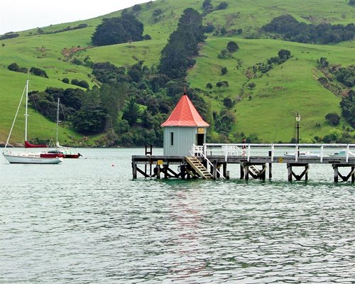 A pier and boats on the ocean alongside the mountains.