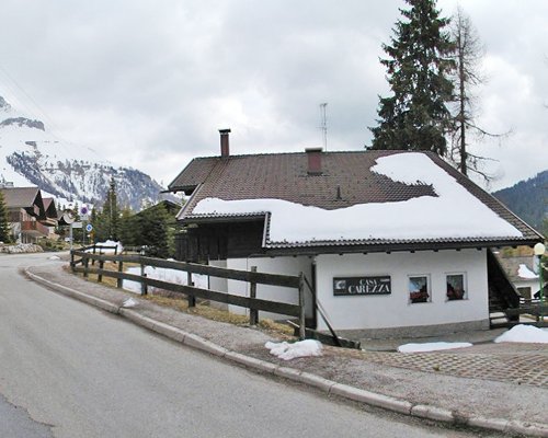 A street view of the Casa Carezza resort alongside the mountains covered in snow.