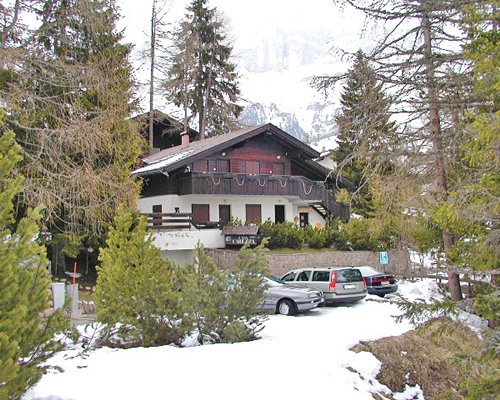 An exterior view of the Casa Carezza resort with a parking lot covered in snow.