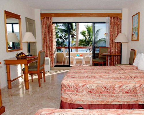 A well furnished bedroom with king bed balcony and patio chairs.