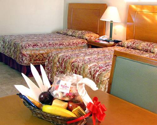 An open plan bedroom with two beds and a dining table.