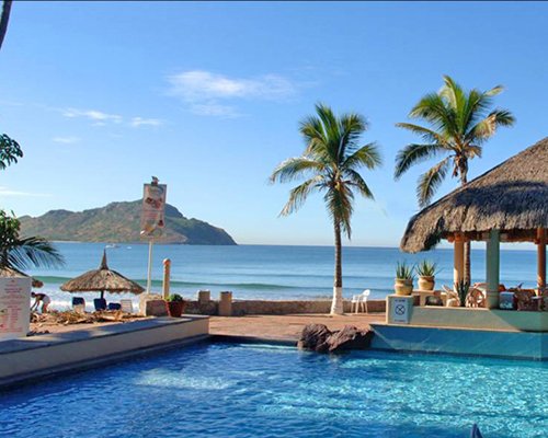 An outdoor swimming pool with poolside bar alongside the ocean.