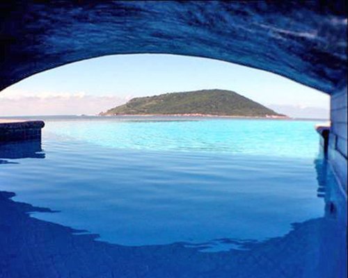 View of the ocean and hillock from under a bridge.