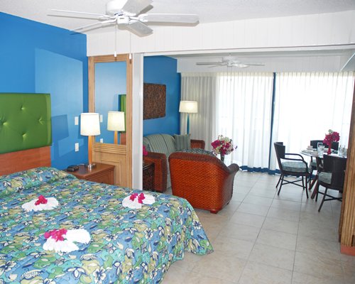 A well furnished bedroom with a king bed alongside living and dining area.