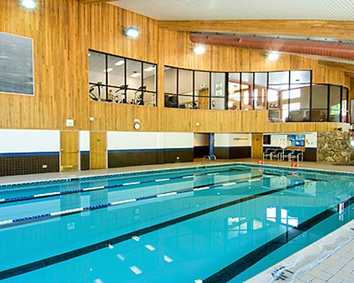 An indoor swimming pool alongside a well furnished area.