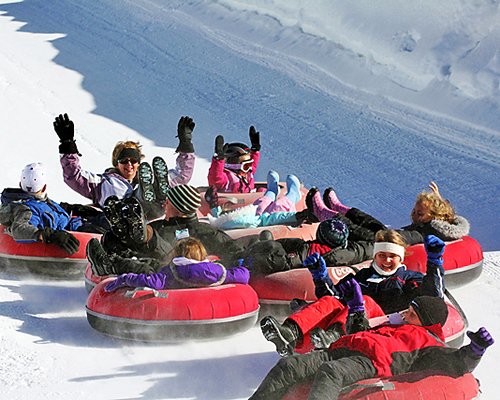 A group of people enjoying snow tubing in the ice.