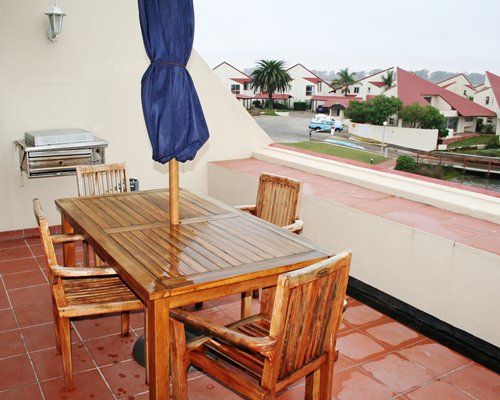 Balcony with patio furniture umbrella and barbecue grill.