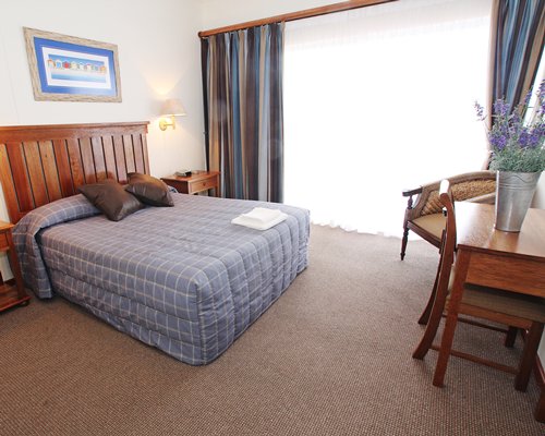 A well furnished bedroom with queen bed and outside view.