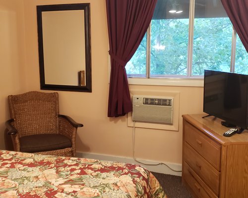 A bedroom with large bed television and window.