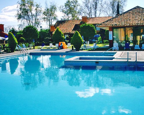 An outdoor swimming pool with chaise lounge chairs and a poolside bar.