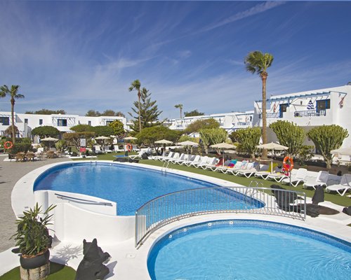 Outdoor swimming pool with chaise lounge chairs and sunshades .