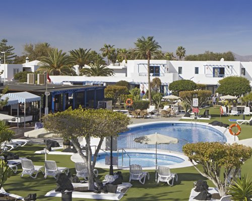 An outdoor swimming pool with hot tub and chaise lounge chairs sunshades.