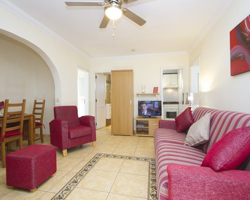 A well furnished living room with a television dining area and open plan kitchen.