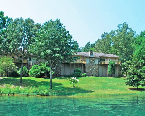 Exterior view of Los Indios Escapes Cherokee Village alongside the lake surrounded by wooded area.