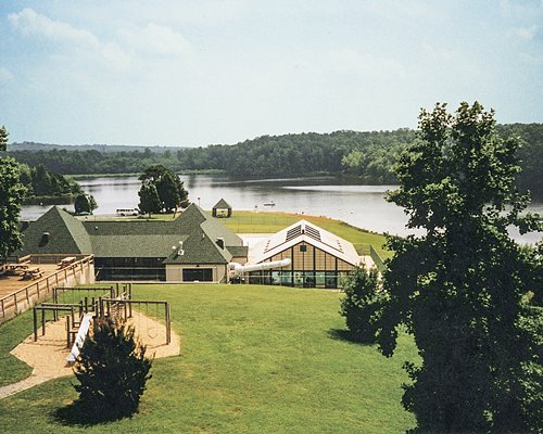 Scenic view of playground with kids playscape alongside the lake surrounded by wooded area.