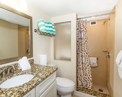 A bathroom with stand up shower and single sink vanity.