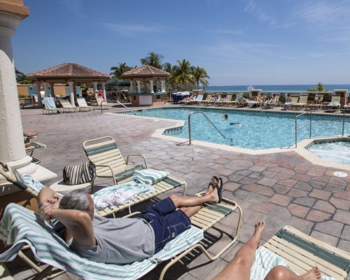 An outdoor swimming pool with chaise lounge chairs alongside the beach.