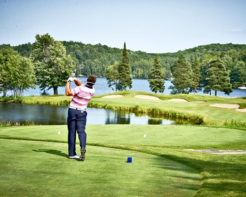 Golfer at the course course alongside a lake.