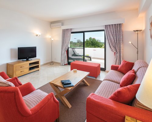 A well furnished living room with a television and balcony.